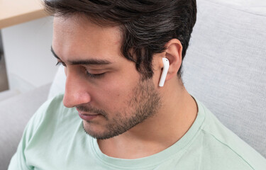 Fototapeta premium Close-up photo of young man in wireless earphones listening to music