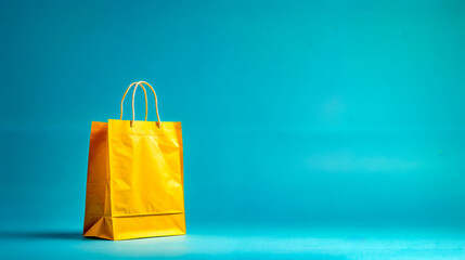 Yellow shopping bag sitting on blue surface with light blue background.