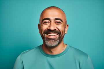 Obraz premium Happy Middle Eastern bald man, 45 years old, winking on a pastel teal background