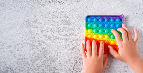 Top view of rainbow antistress sensory toy fidget push pop it on stone background