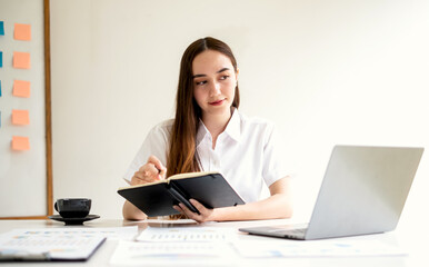 Asian businesswoman sit at their desks and calculate financial graphs showing results about their...