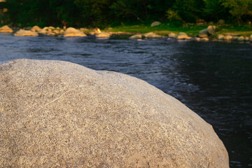 yellow stone in focus with river in the forest