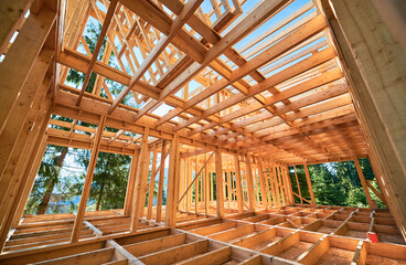Under-construction residential wooden frame home located near a forest. Commencement of a new...
