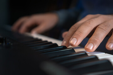 Fototapeta premium Close-up of male hands playing an electronic piano. Musical education at a music school. Private music lessons with a teacher.