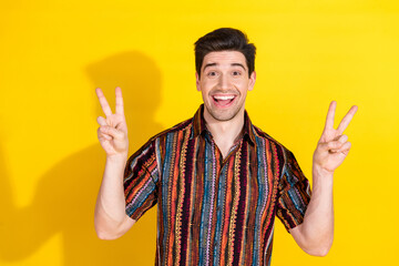 Photo of nice young man show v-sign wear shirt isolated on yellow color background