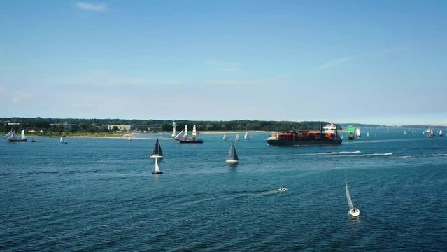 Container ship and tall ships passing Kieler F&ouml;rde to Kiel week. Parade of sailing ships during Kiel Week, Kiel Fjord, Schleswig-Holstein, Germany.