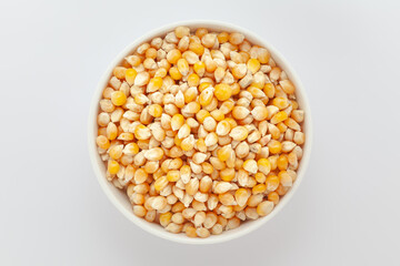 Organic Corn Seeds (Zea mays) or Makka, in a white ceramic bowl. Isolated on a gray background. Top View