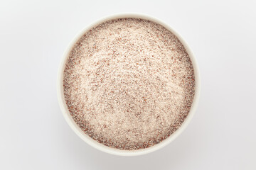 Organic Ragi (Eleusine coracana) or Finger Millet Flour in a white ceramic bowl. Isolated on a grey background. Top View