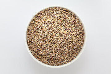 Organic Pearl Millet (Pennisetum glaucum) or Bajra, in a white ceramic bowl. Isolated on a gray background. Top View