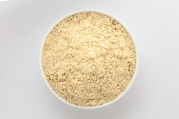 Organic Chikpea Flour (Cicer arietinum) or Besan, in a white ceramic bowl. Isolated on a gray background. Top View