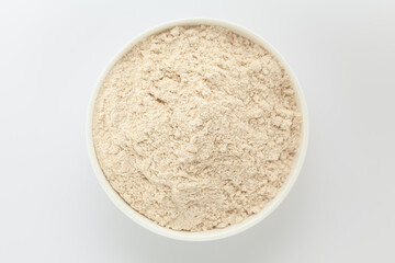 Organic Wheat flour (Triticum) in a white ceramic bowl. Isolated on a gray background. Top View