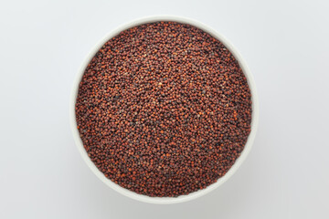 Organic Ragi (Eleusine coracana) or finger millet, in a white ceramic bowl. Isolated on a gray background. Top View