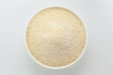 Organic Rice Flour (Oryza sativa) in a white ceramic bowl. Isolated on a grey background. Top View