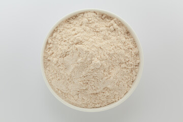 Organic Wheat Flour (Triticum), in a white ceramic bowl. Isolated on a gray background. Top View