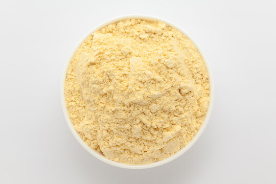 Organic Corn Flour (Zea mays) or Makka Flour, in a white ceramic bowl. Isolated on a gray background. Top View
