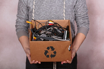 Female hands carrying cardboard box filled with old digital devices, advocating for sustainable...