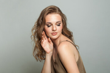 Female model face. Woman with makeup, curly hairstyle and fresh skin on white background