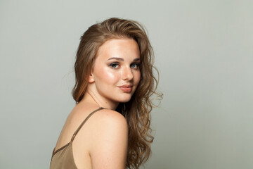 Fototapeta premium Happy young lady with makeup and long wavy hair, closeup portrait. Beautiful woman