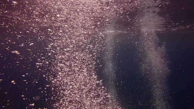 Air bubbles in the blue water on sulight backround in sundown, Slow motion of air bubbles floating from sea bottom to the water surface with waves