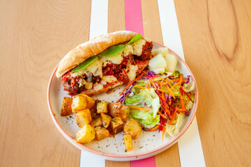 Meatball sub sandwich in baguette bread served in a cafe with sautéd vegetables.