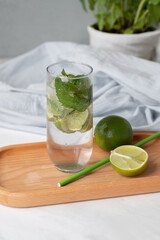 Homemade mojito cocktail drink, limes, drinking straw on kitchen table, summer home cooking