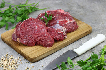 Daging sapi mentah or raw beef on preparation for cooking with some spice. Beef on Eco friendly package and chopping board with wooden rustic background.