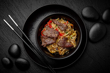 Wok noodles udon with beef. Composition on black background. The Art of Japanese Cuisine. Food photography for menu and sushi bar decoration