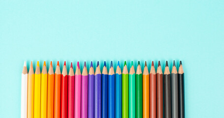 Color pencils collection in a row, back to school, drawing supplies, blue background with copy space