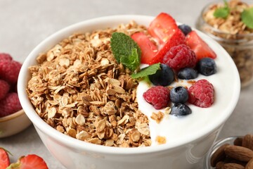 Tasty granola with berries and yogurt in bowl on grey table, closeup