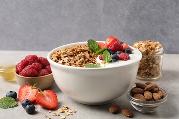 Tasty granola with berries and yogurt in bowl on grey table, closeup