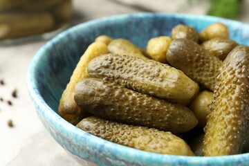 Pickled cucumbers in bowl on grey table, closeup