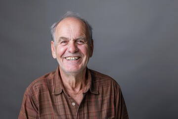 Obraz premium Portrait of a happy caucasian man in his 60s smiling at the camera over blank studio backdrop