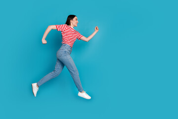 Full length photo of adorable lovely girl wear striped t-shirt jumping high walking empty space...