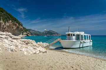 Fototapeta premium Tourism cruise boat at Cala Luna beach and clear transparent blue water in the Gulf of Orosei, Sardinia island, Italy