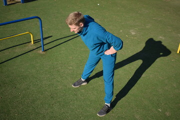 Obraz premium A focused young athlete dynamically performing warm-up drills and stretches outdoors. Clad in athletic gear, he meticulously prepares body for the physical demands ahead through a regimented routine