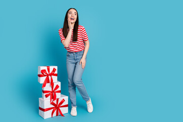 Full length photo of adorable excited girl wear striped t-shirt choosing presents empty space...