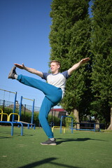 A focused young athlete dynamically performing warm-up drills and stretches outdoors. Clad in...