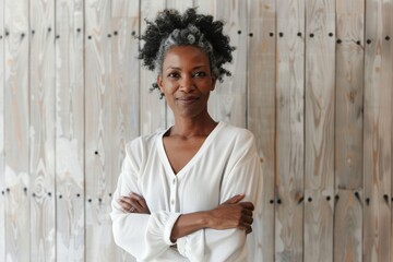 Portrait of a satisfied afro-american woman in her 50s with arms crossed in light wood minimalistic setup
