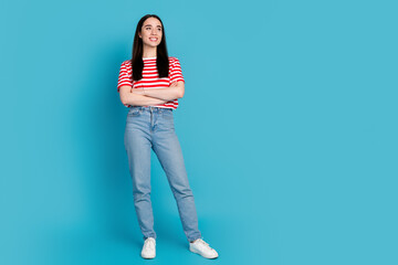 Full length photo of charming positive girl wear striped t-shirt arms folded looking empty space isolated blue color background