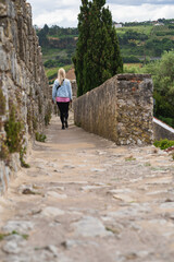 Girl tourist in the city of Obidos fortress, view from the back.