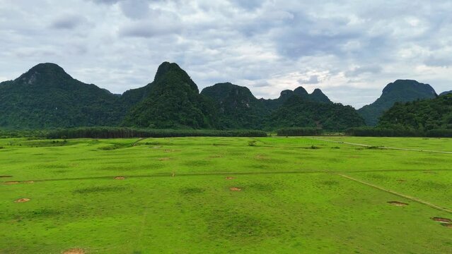 Aerial view impression nature by drone of Tu Lan, Quang Binh, Vietnam, majestic limestone mountain range with river around, meadow at foothills, natural unique for Vietnam adventure