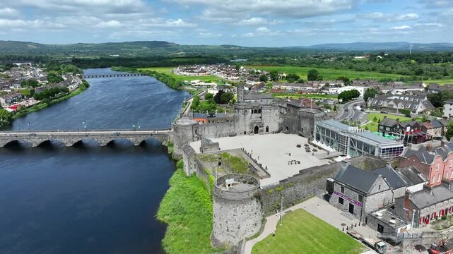 King John's Castle, Limerick, Ireland, May 2024. Drone orbits the Medieval Castle on the River Shannon with views west revealing St. Munchin's church and Thomond Park Stadium in the distance.
