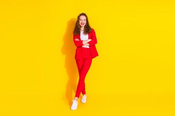 Full body portrait of gorgeous young lady crossed arms empty space wear red suit isolated on yellow color background