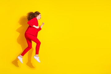 Full body profile portrait of gorgeous young lady jump run empty space wear red suit isolated on yellow color background