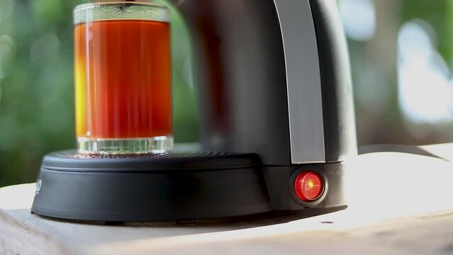 Hand turning on a coffee maker using a red switch The switch is labeled ON OFF in white letters. The coffee maker is black and has a glass carafe on the front.
