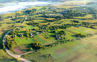 Village in morning mist. Farm house rural fog. House in rural landscape, drone view. Countryside at dawn in fog, aerial view. Roofs of Country houses in Foggy dawn. Rural landscape, aerial view.