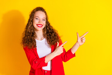 Portrait of gorgeous young lady point fingers empty space wear red suit isolated on yellow color background