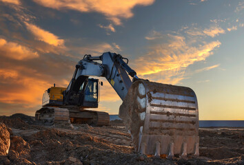Excavator on sunset background. Open-pit mining. Backhoe dig ground in quarry. Heavy construction...