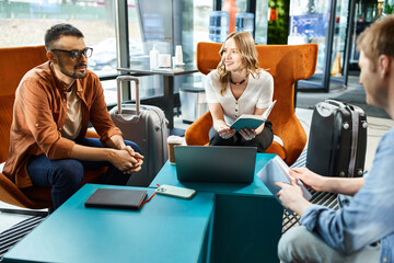 Multicultural colleagues in casual attire gathered around a table with luggage, discussing during a...