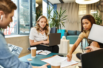 A diverse group of professionals collaboratively working on laptops at a modern workspace table.